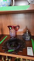 Photo showing all three items: lidded trinket box, pitcher, and cake plate on wooden shelf.