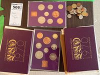 Two 1970 coin sets with purple cases and a pile of loose spare coins on a brown mat.