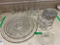 Three nested glass platters with textured Cornflower pattern, plus other pieces (narrows, footed bowls) arranged on a table, with glasses behind.