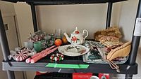 Shelf display showing all items including Royal Albert Poinsettia teapot, cake plate, candles, stockings, tealight holders, and faux fruit.
