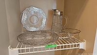 Shelf display showing silver overlay cake plate, platter, pedestal bowl, and pressed glass pitcher