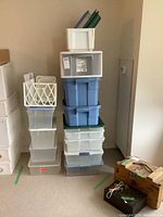 Stack of various storage bins in blue, clear and white with some lids missing.