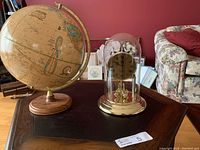 Wide view showing both the carriage clock under glass dome and the Crams Imperial World globe on oak stand.