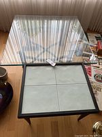 Top view of smaller coffee table with four large light-colored ceramic tiles framed in black metal.
