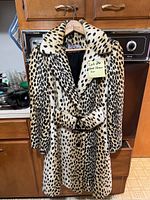 Front view of leopard print faux fur coat with belt on wooden hanger