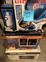 Stack of boxed small kitchen appliances including George Foreman grill, Mr. Coffee grinder, Black & Decker Spacemaker drip coffeemaker, Black & Decker Toast-R-Oven toaster oven.