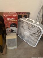 Photo showing Lasko ceramic heater box, small white ceramic heater, and white box fan.