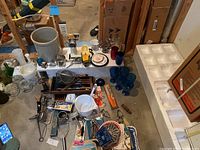 Overview of entire lot showing a wide assortment of kitchen gadgets, utensils, glassware, dishes, and crocks laid out on floor