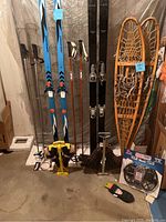 Photo of the entire lot showing cross country skis, alpine skis, ski boots, ski poles, wooden snowshoes, and traction devices.