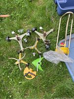 Four sprinklers and small sprinkler parts on grass next to a plastic bin.