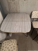 Top view of vintage rectangular drop leaf table in grey wood veneer with metal hairpin legs