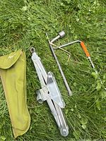 Photo of Toyota metal scissor jack with handle and storage bag placed on grass