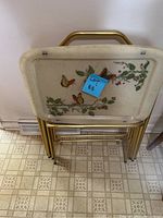 Front view of stacked TV trays showing butterfly and floral design on top tray.
