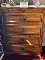 Frontal view of the wooden dresser showing four drawers and brass handles.