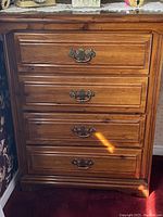 Front view of the first 4-drawer wooden dresser with brass handles, showing the grain and panel detailing.