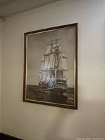 Framed poster of the Bluenose ship showing the full ship with sails on the water, in a wooden frame with gold trim.