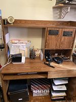 Desk shown with various items on top, including a clock, printer, and electronics, highlighting structure and condition.
