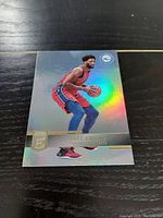 Front side of Joel Embiid Panini Prizm Elite basketball card showing holographic image of player in action.