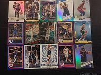 Photo showing 15 NBA basketball cards arranged in three rows with various player images and holographic foiling.