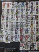 Photo showing 42 Panini Contenders Ticket football cards laid out in rows on a dark surface, various players and NFL teams visible, cards appear in good condition.