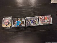 Four Premier League trading cards arranged side by side on a dark surface showing various series and players including Christian Nørgaard and others.