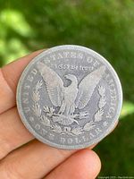 Back side of the 1888 American silver dollar coin showing eagle with arrows and olive branch, inscriptions 'UNITED STATES OF AMERICA', 'In God We Trust', and 'ONE DOLLAR'.