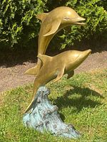 Front view of two dolphins rising from wave base on grass surface