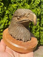 Close-up view of solid bronze eagle head sculpture showing left profile and detail of feathers and eye.