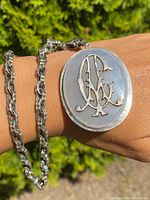 Necklace worn on wrist showcasing chalcedony oval pendant with silver Victorian monogram