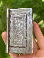 Front cover view of the silver snuff box with detailed floral embossed decoration on a textured background and circular border pattern
