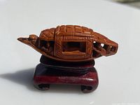 Side view of the antique carved peach pit boat showing detailed carving and figures inside the boat mounted on a wooden stand.