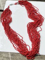Full length view of the multi-stand coral necklace showing red beads and silver clasp.