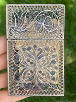 View of the front and top of the antique silver filigree card case showing detailed floral wirework on silver background.