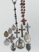 Overview of all religious pendants, crosses, and rosary beads on white background