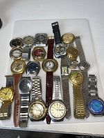 Photo showing a collection of 18 vintage Timex wristwatches laid out on a white surface, various dial colors and band styles.