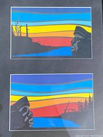 Close-up photo of Roy Henry Vickers serigraph prints with vivid colorful landscape silhouettes and signed numbering details.