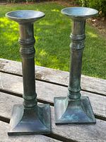 Pair of candlesticks upright on wood surface with lawn background