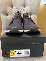 Front view of Adidas NMD R2 sneakers placed on top of original black Adidas box showing size 10 label.