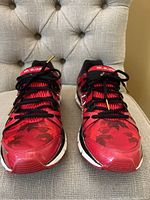 Front view of ASICS Team Canada Olympic men's running shoes showcasing red and black design with maple leaf pattern and black laces.