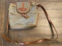 Full view of the green leather Balmain crossbody bag showing the adjustable brown leather strap and drawstring closure.