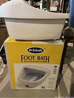 White electric foot bath massager on top of original yellow Dr. Scholl's Foot Bath Massager retail box.