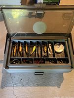 Overview of closed top lid showing clear plastic top and partially visible lures inside compartments