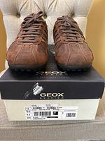 Front view of the brown Geox nubuck leather shoes on the Geox box showing shoe shape, laces, and texture.