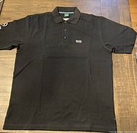 Full view of black Hugo Boss short sleeve polo shirt laid flat showing front and sleeves.