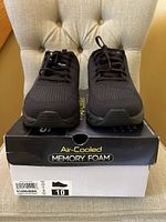 Front view of black Skechers sneakers on original Skechers Air memory foam box, showing the shoe size label (US 10) on the box.