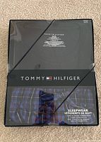 Front of the original Tommy Hilfiger pyjama box set showing the navy top and check pants through clear packaging.