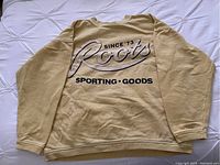 Full front view of yellow oversized Roots crewneck sweatshirt laid flat showing printed graphic text