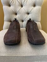 Front view of the pair of brown Skechers leather shoes showing toe area and upper leather surface with visible stitching and slight wear marks.