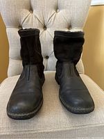 Front view of the pair of black Ugg boots showing leather and suede materials, worn condition visible.
