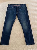 Front view of Wrangler men's blue slim jeans laid flat on surface showing overall condition and color.